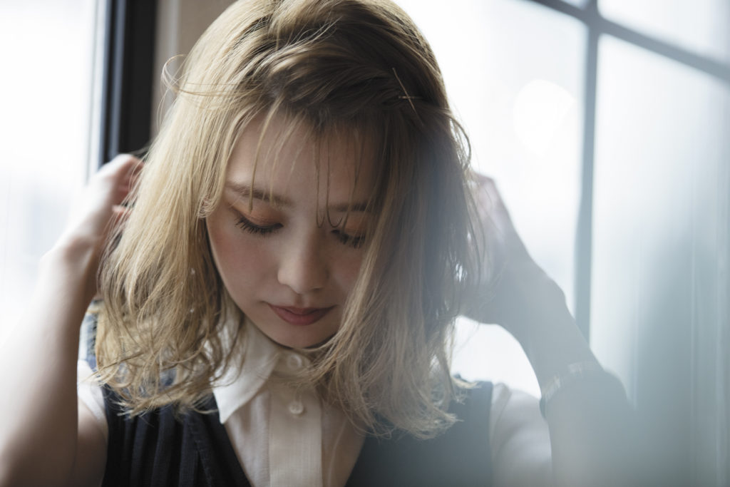 スタイリング剤を使用して自分でヘアセットしている女性